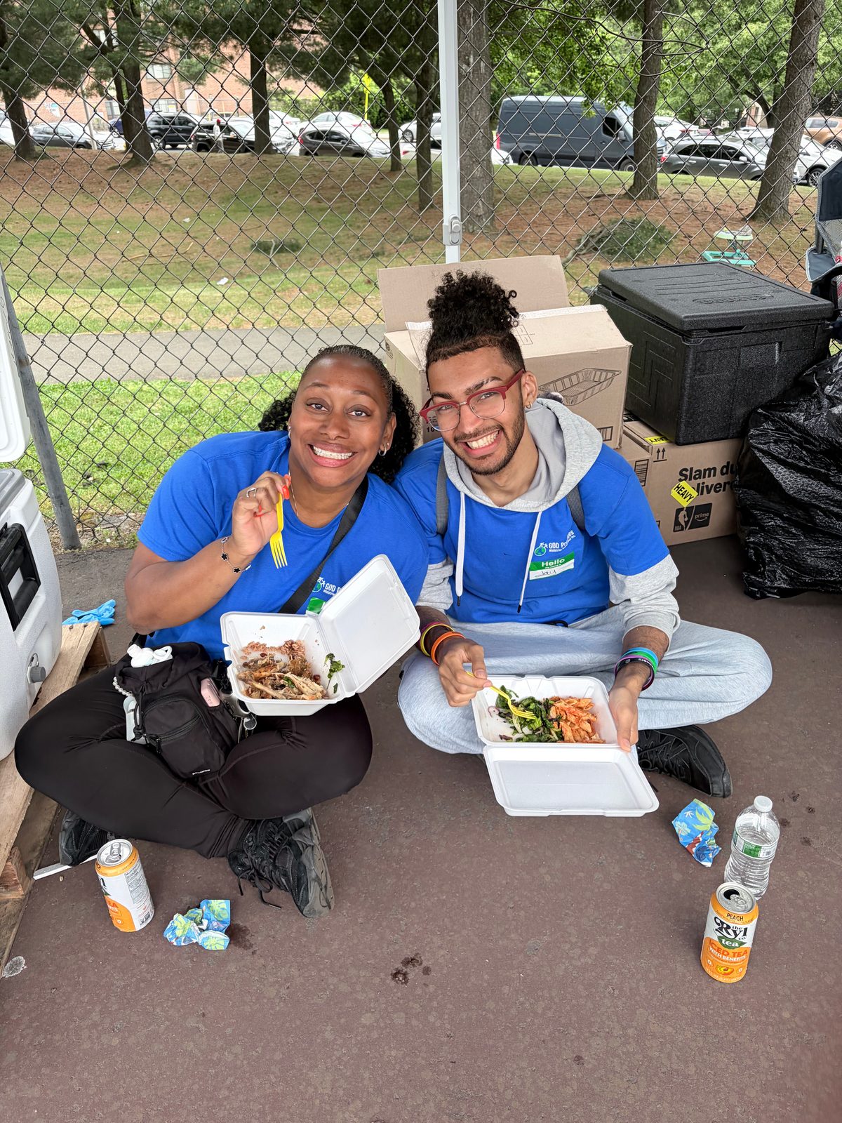 Two Village volunteers smiling after serving meals to the community